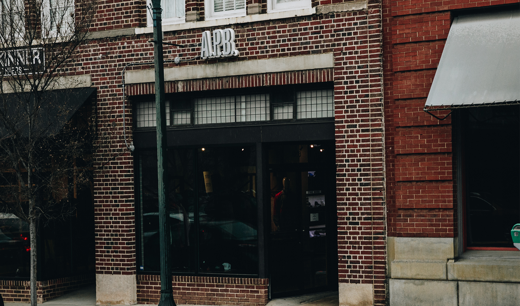 Brick storefront with APB sign, large windows, and street view, urban retail exterior