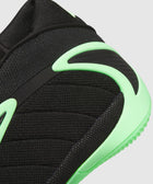 Close-up of black and neon green men's sneaker with mesh texture and curved sole accents
