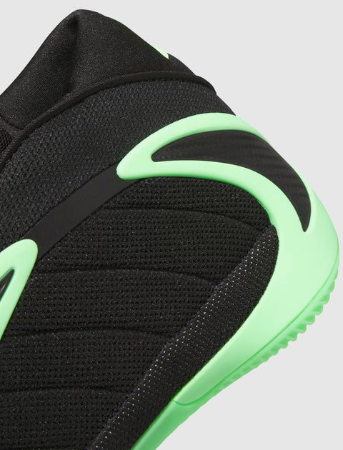 Close-up of black and neon green men's sneaker with mesh texture and curved sole accents