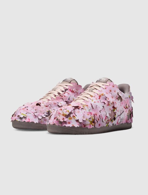 Low-top sneakers with pink cherry blossom floral 3D appliqué design on a gray sole