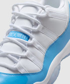 Close-up of white and light blue low-top sneaker with white laces and glossy accents