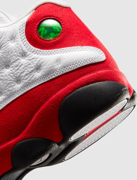 Close-up of red, white, and black sneaker heel with green holographic detail, textured sole