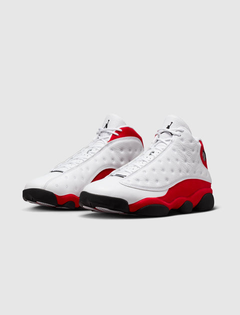 White and red retro basketball sneakers with textured leather and black outsoles on gray background.