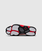 Red and black sneaker with white rubber sole, viewed from the bottom on a light background