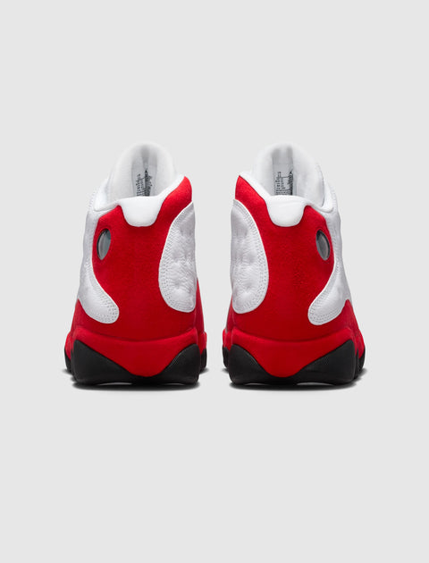 Rear view of white and red high-top sneakers with black soles on a plain background