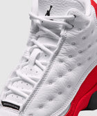Close-up of white and red high-top sneaker with textured leather and black logo on tongue
