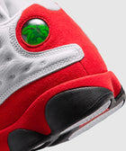 Close-up of a white and red suede sneaker heel with green holographic detail and black outsole