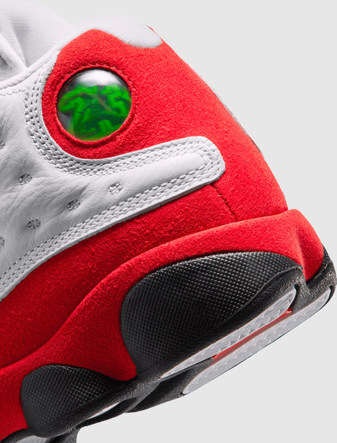 Close-up of a white and red suede sneaker heel with green holographic detail and black outsole