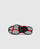 Red, black, and white sneaker outsole with herringbone traction pattern on grey background