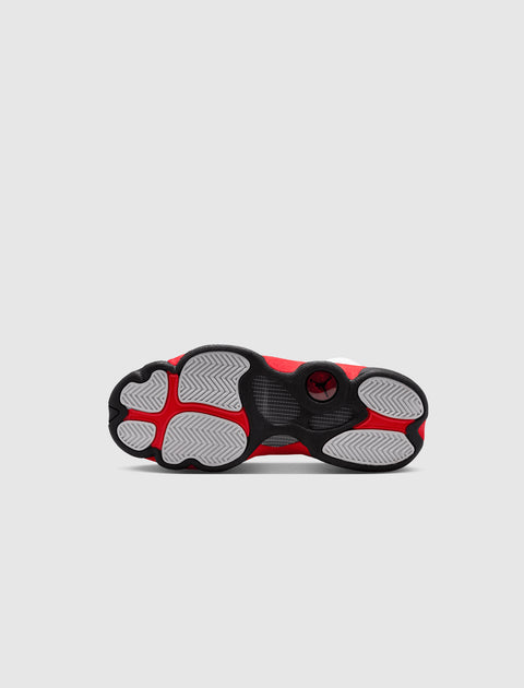 Red, black, and white sneaker outsole with herringbone traction pattern on grey background