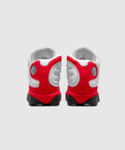 Back view of white and red athletic sneakers with black soles on a plain background