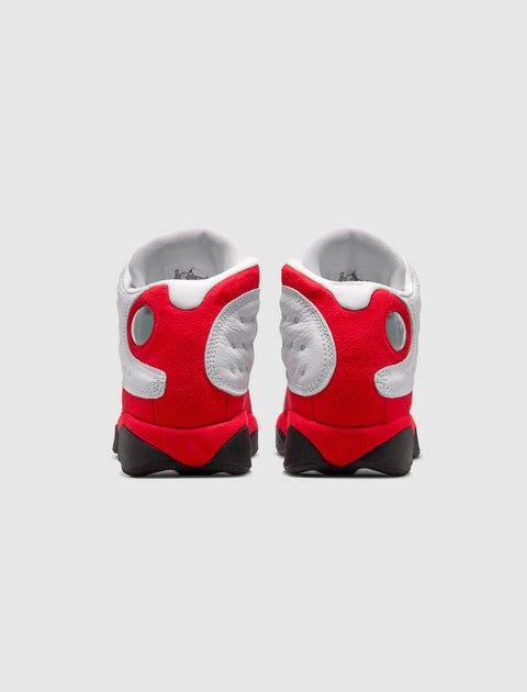 Back view of white and red athletic sneakers with black soles on a plain background