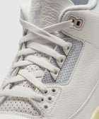 Close-up of white leather sneaker with perforated panels and white laces.