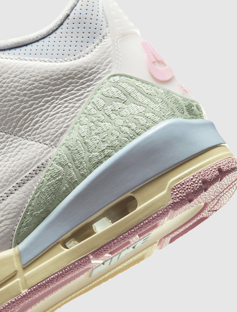 Close-up of a white and pastel Nike sneaker featuring textured leather, mint green and pink accents.