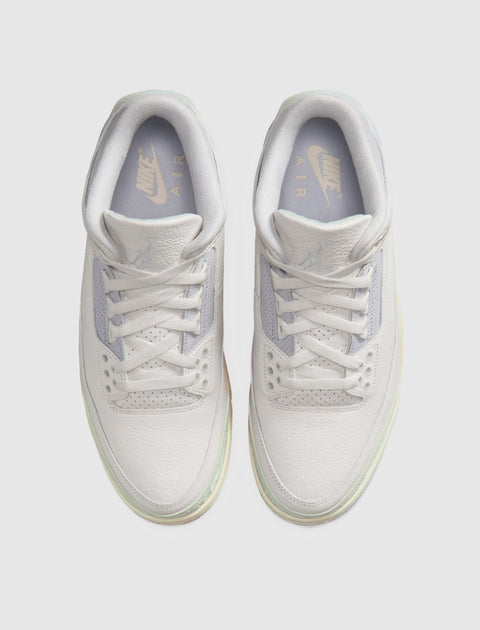 Top view of white Nike Air Jordan 3 sneakers with pastel accents on a light background