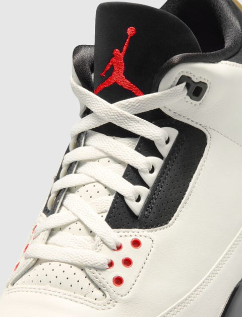 White and black sneaker with red Jumpman logo and red lace eyelets, closeup view