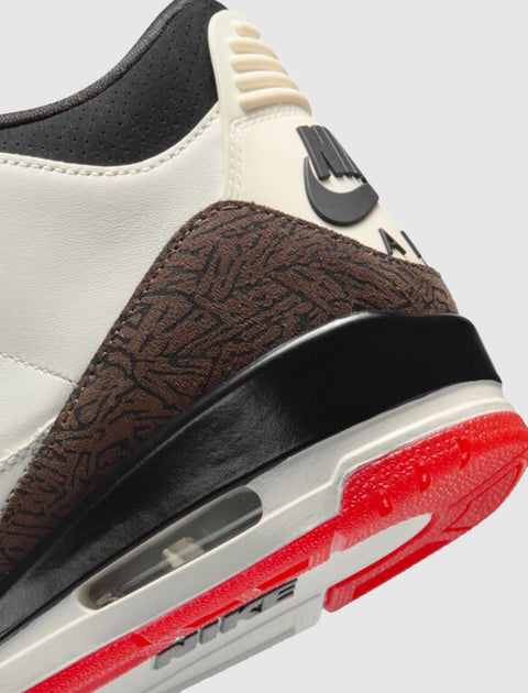 Close-up of Nike Air sneaker heel with brown textured panel, visible air sole, and red outsole