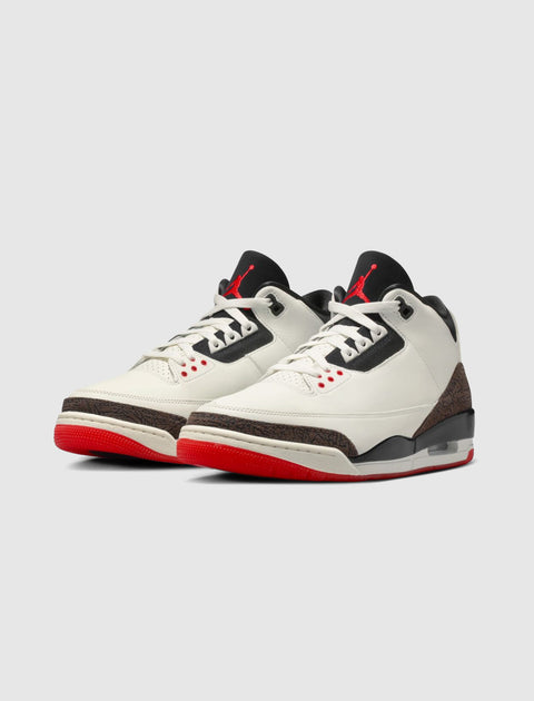 White and black sneakers with red soles, elephant print accents, and visible air cushioning