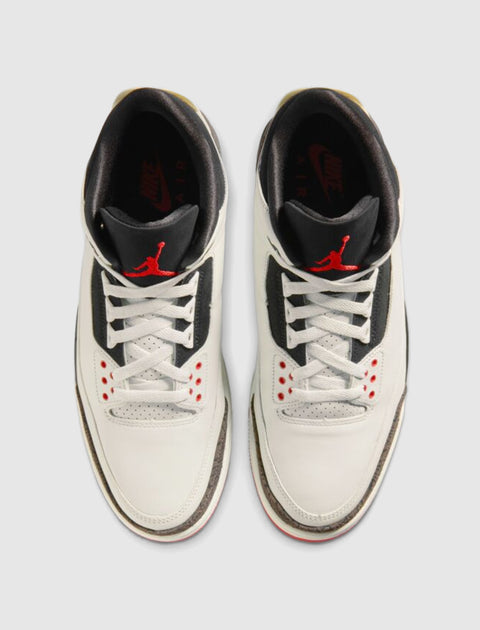 White and black men's sneakers with red accents, viewed from above on a neutral background