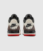 Back view of white and brown Nike Air sneakers with red soles and black logo detailing