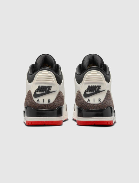 Back view of white and brown Nike Air sneakers with red soles and black logo detailing