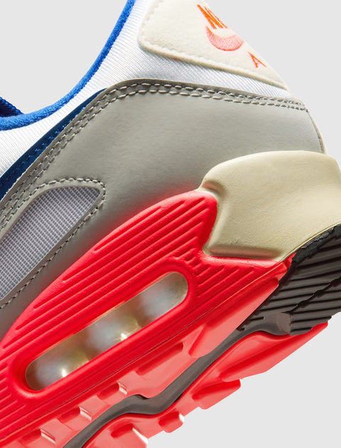 Close-up of an athletic sneaker with a red outsole, air cushion, and grey upper accents