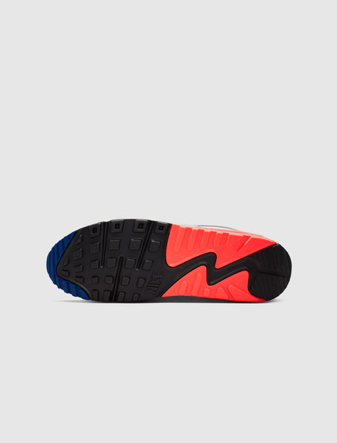 Black, blue, and red sneaker outsole with textured tread pattern on a white background