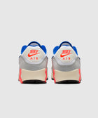 Back view of Nike Air Max 90 sneakers in grey, blue, and bright red colorway on white background