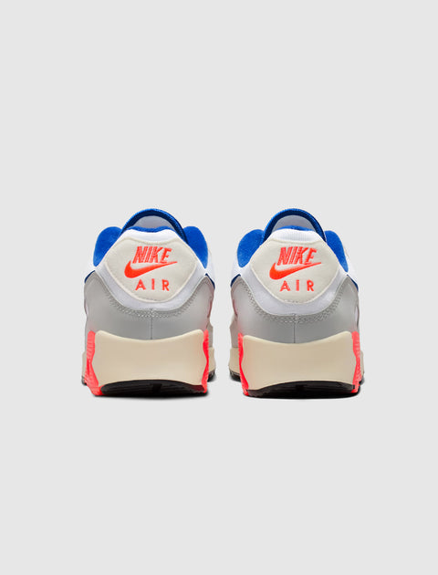 Back view of Nike Air Max 90 sneakers in grey, blue, and bright red colorway on white background