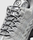 close-up of silver mesh and synthetic men's sneaker with '95' logo on tongue