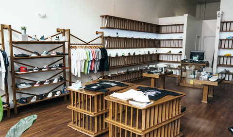 Modern streetwear store interior with sneakers, t-shirts, hats, and wooden display shelves.