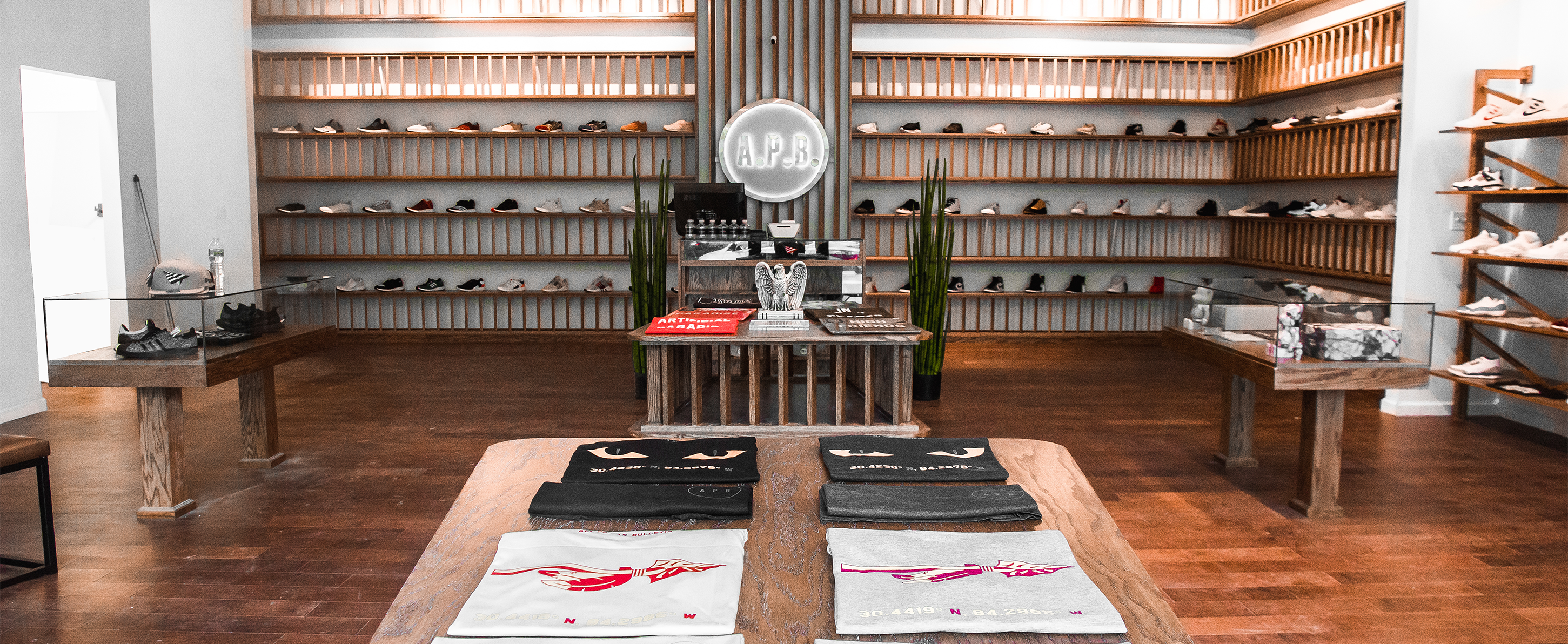 Modern streetwear store interior with sneakers on wooden shelves and folded graphic tees on tables