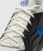 Close-up of white and black sneaker with holographic tongue logo and blue Nike Swoosh