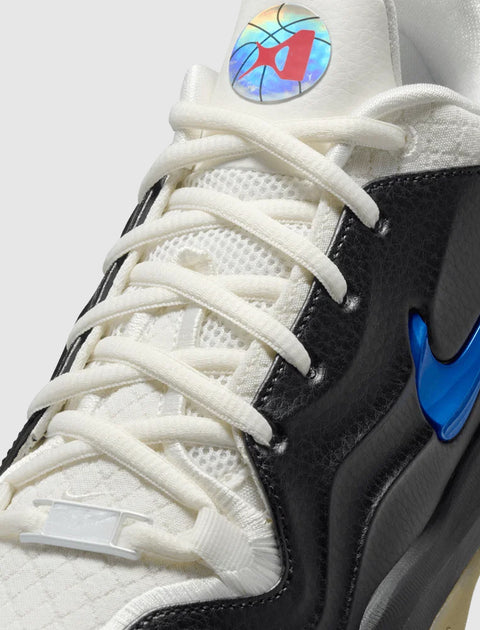 Close-up of white and black sneaker with holographic tongue logo and blue Nike Swoosh