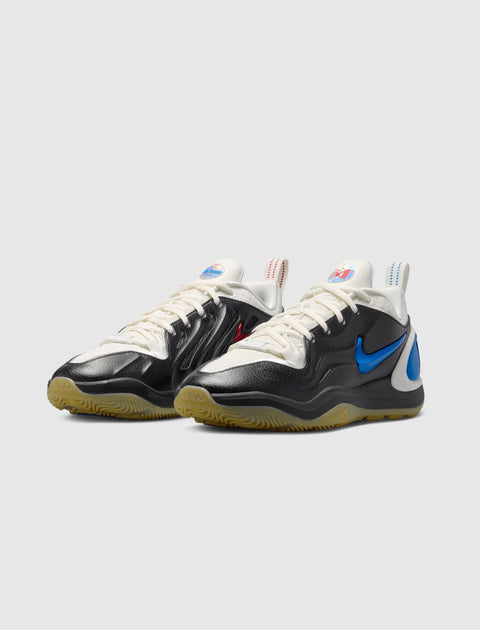Black and white low-top sneakers with blue side swoosh, gum sole, and unique heel tabs.