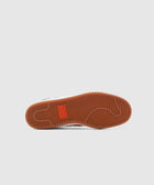 Close-up of sneaker gum sole with herringbone tread pattern on light background