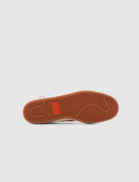 Close-up of sneaker gum sole with herringbone tread pattern on light background