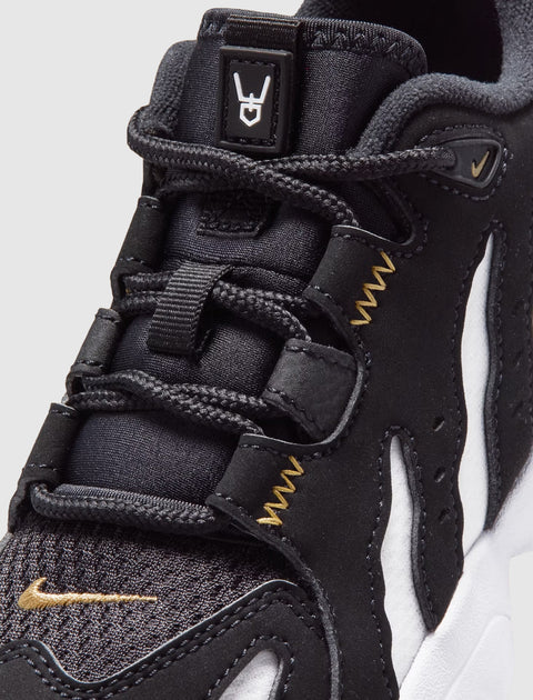 Close-up of black and white sneaker with gold stitching and textured laces