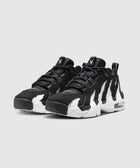 Black and white men's sneakers with gold accents and chunky soles on a light background