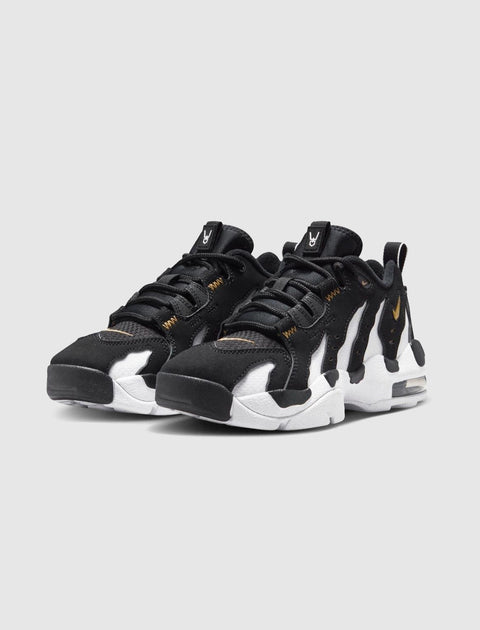 Black and white men's sneakers with gold accents and chunky soles on a light background