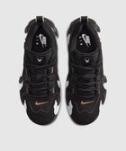 Black and white Nike Air sneakers with gold swoosh, viewed from above on a light background.