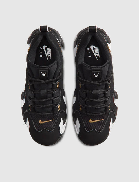 Black and white Nike Air sneakers with gold swoosh, viewed from above on a light background.