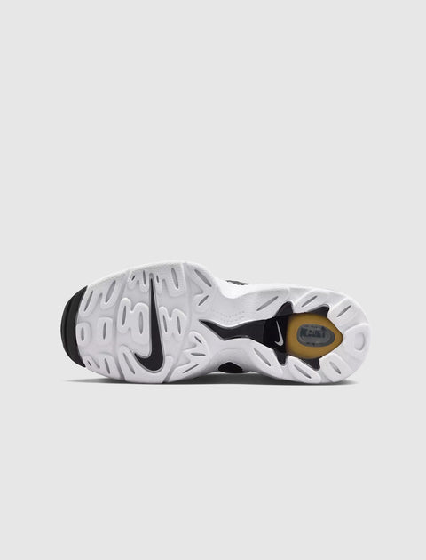 Closeup of white sneaker outsole with black and yellow accents, Nike logo visible