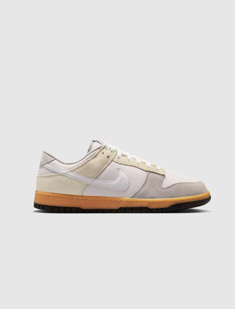 Low-top grey and beige suede sneaker with white swoosh and gum sole on white background