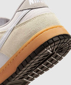 Close-up of sneaker heel with beige suede, white canvas, gum sole, and black tread