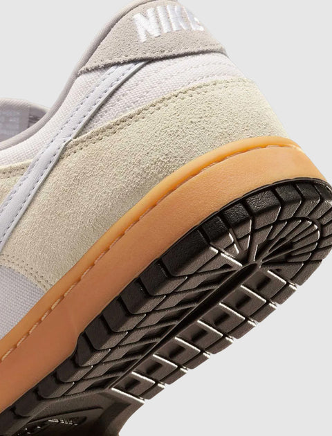 Close-up of sneaker heel with beige suede, white canvas, gum sole, and black tread
