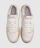 Top view of grey and white low-top sneakers with gum soles on a light background