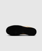 Close-up of black rubber sneaker outsole with circular tread pattern on gray background