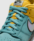 Close-up of Nike SB Dunk Low Pro sneaker with teal and yellow leather upper, blue laces, and iridescent Swoosh logo.