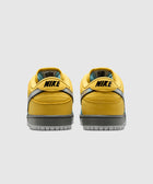 Yellow low-top sneakers with gray soles and black NIKE logo, rear view on white background